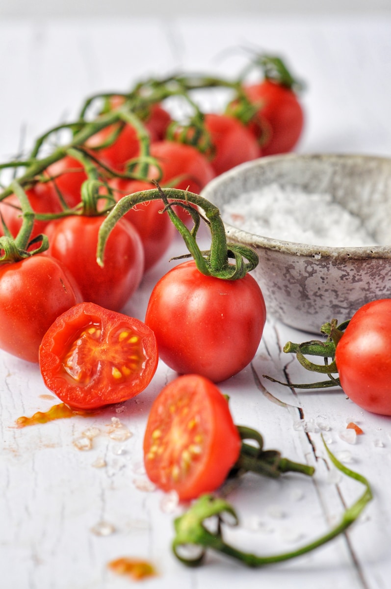 red tomato beside white ceramic bowl